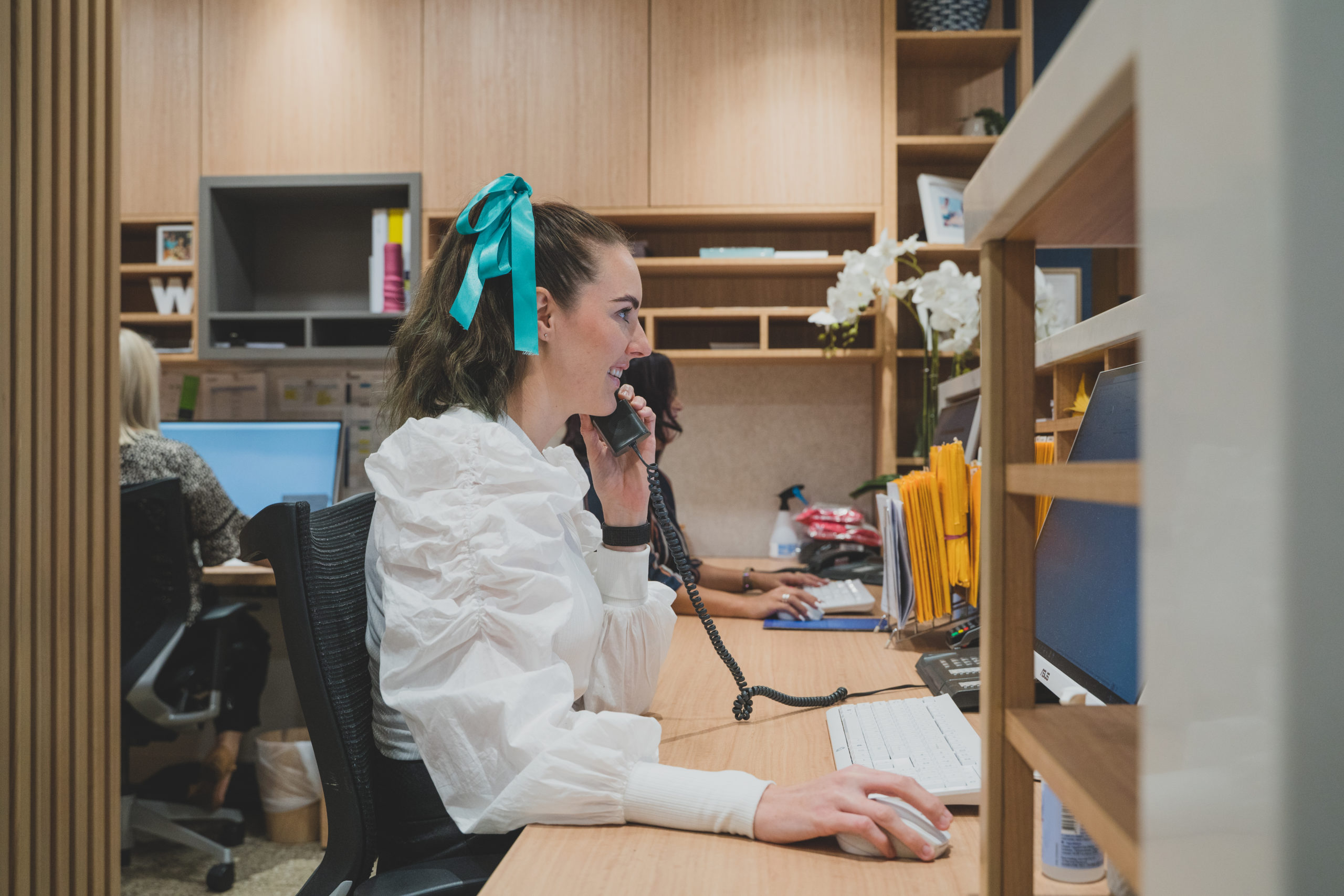 Practice manager on the phone with patient while entering patients data into practice management software