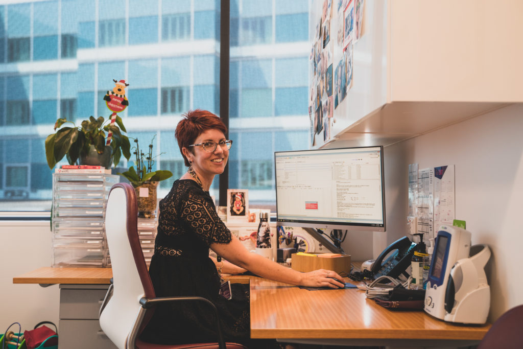 Practice manager sitting at computer using genie solutions software