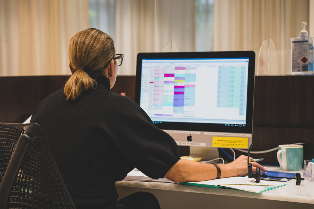 practice manager sitting at computer entering patient data into genie solutions practice management software