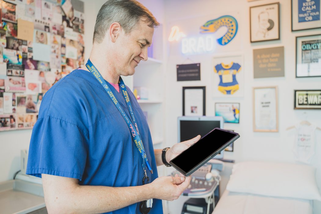 GP holding ipad entering patient data into practice management software